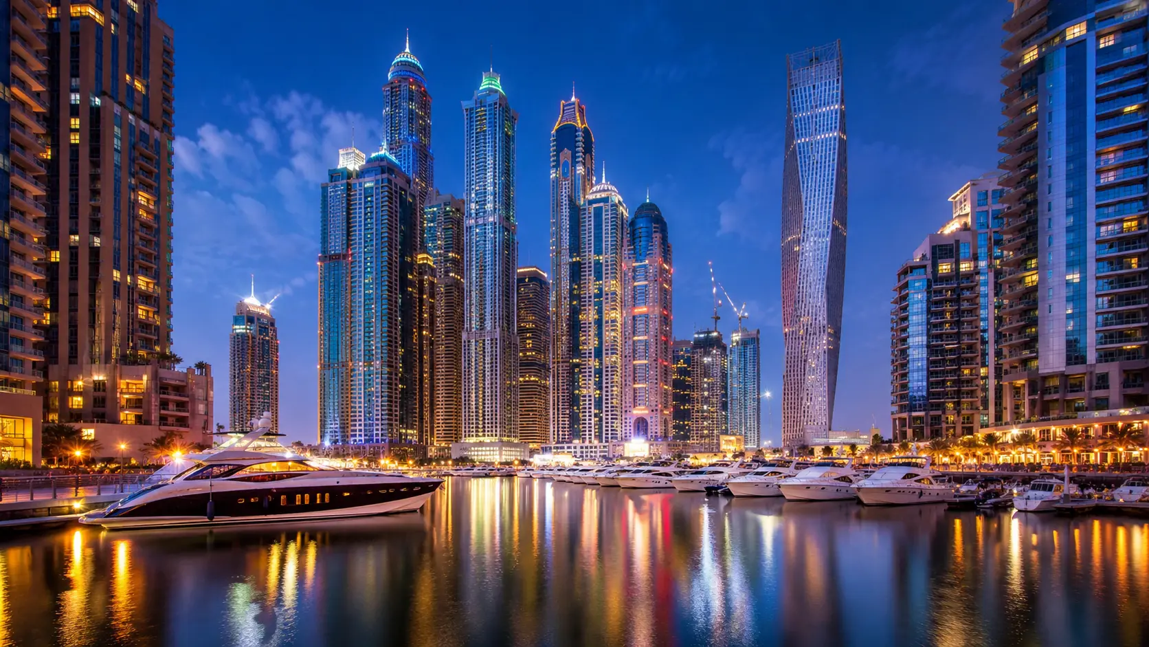 Dubai Marina bei Nacht mit Hochhäusern, Yachten und Spiegelungen im Wasser